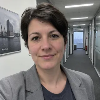 Porträt von Svenja Kröger, Frau Mitte dreißig mit kurzem dunklem Haar und grauem Blazer