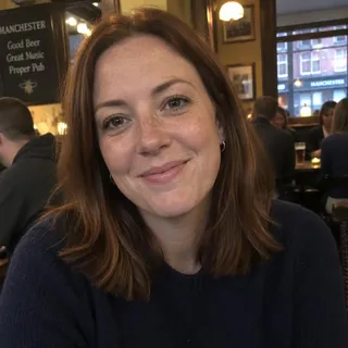 Portrait of Becky Holroyd, a woman in her thirties with shoulder length auburn hair and a navy jumper