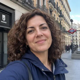 Retrato de Beatriz Casal, mujer de unos cuarenta años con pelo castaño rizado y una chaqueta de color azul marino