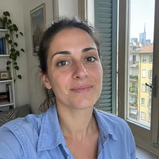 Ritratto di Ilaria Dal Bosco, donna sulla trentina con capelli castani raccolti e camicia blu